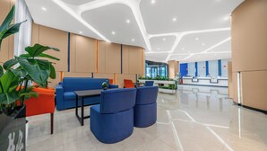 Un hall d’entrée moderne avec un comptoir d’accueil, un espace salon et une grande plante.