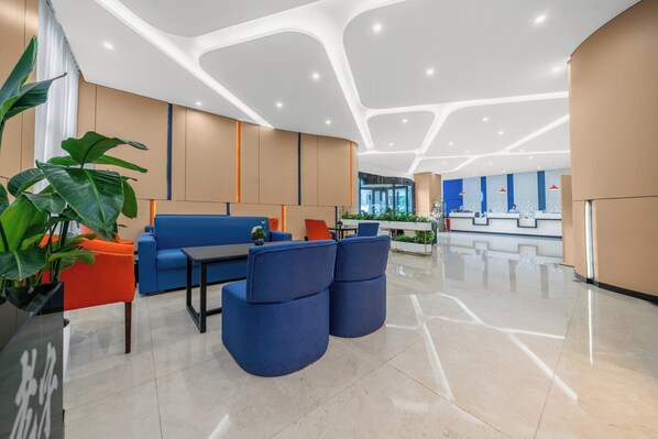 Eine moderne Lobby mit Empfangstresen, Sitzgelegenheiten und einer großen Pflanze.