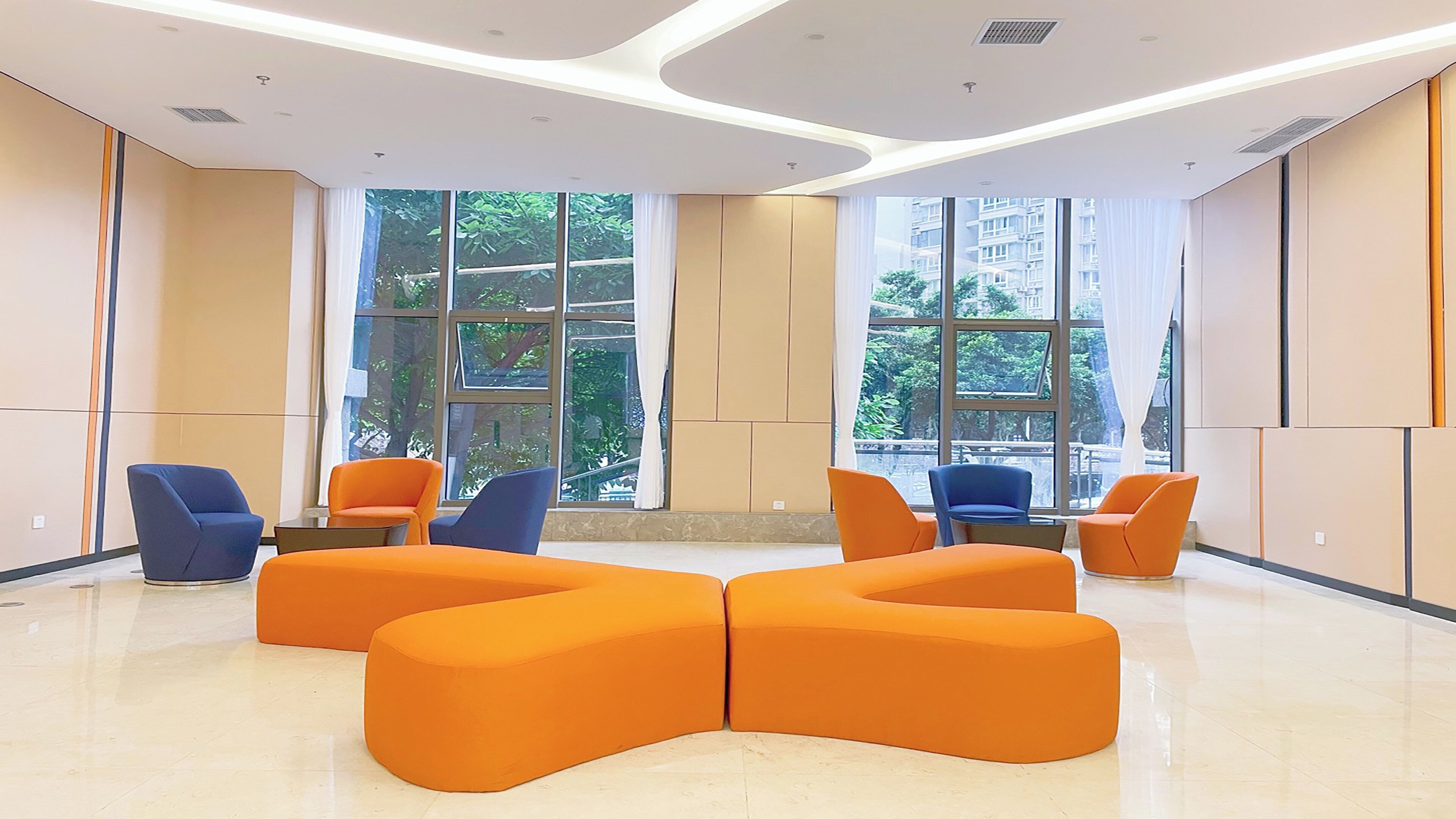 A modern waiting area with orange seating, large windows, and a clean, minimalist design.