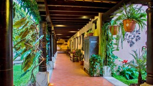 A corridor with tiled flooring, potted plants, and a wooden ceiling structure.