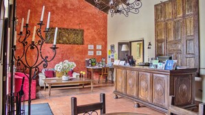 A lobby with a reception desk, wooden paneling, a chandelier, and a red wall.