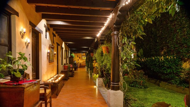 A corridor with tiled flooring, wooden benches, and potted plants.