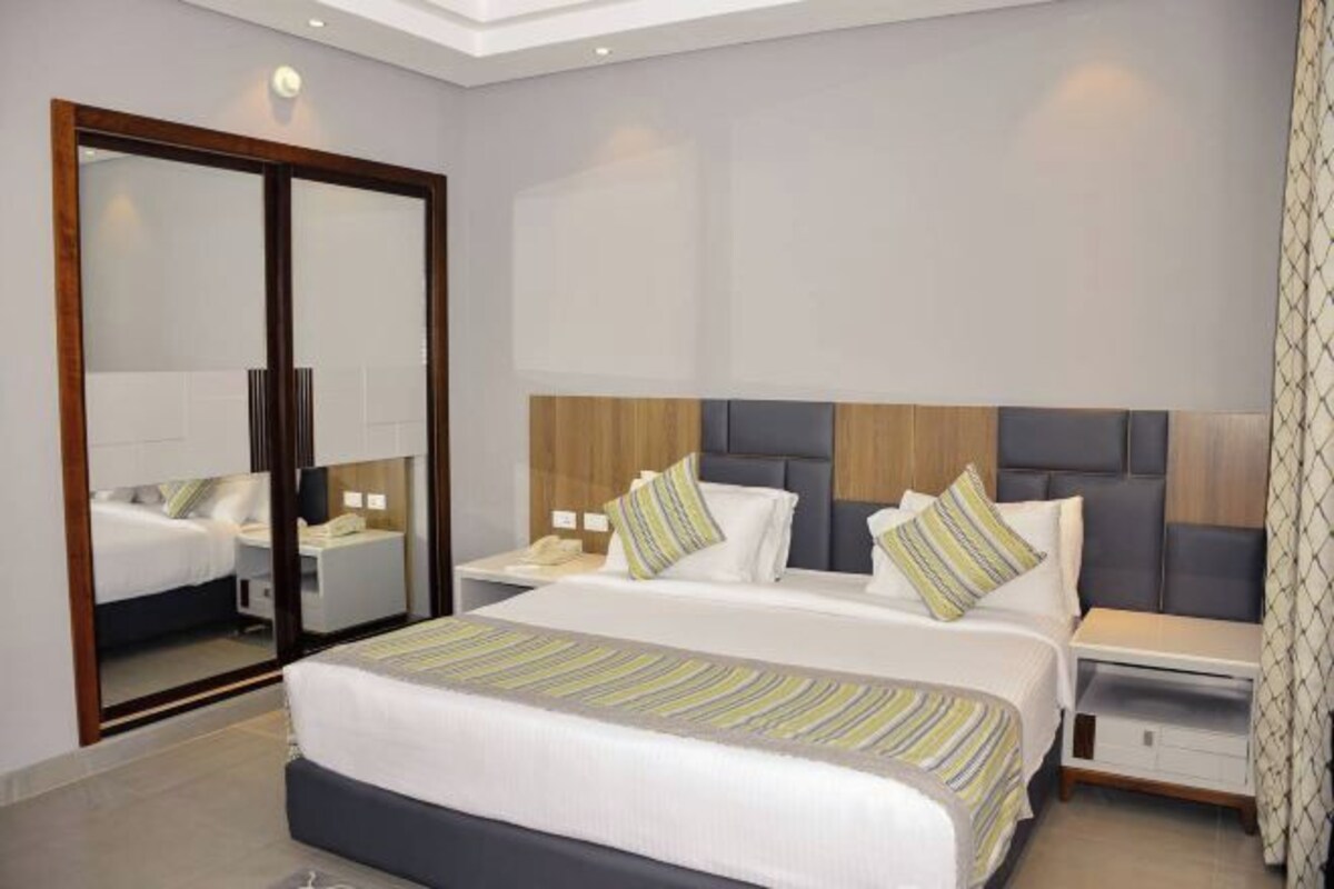 A hotel room with a large bed, a nightstand, a mirror, and a sliding door.