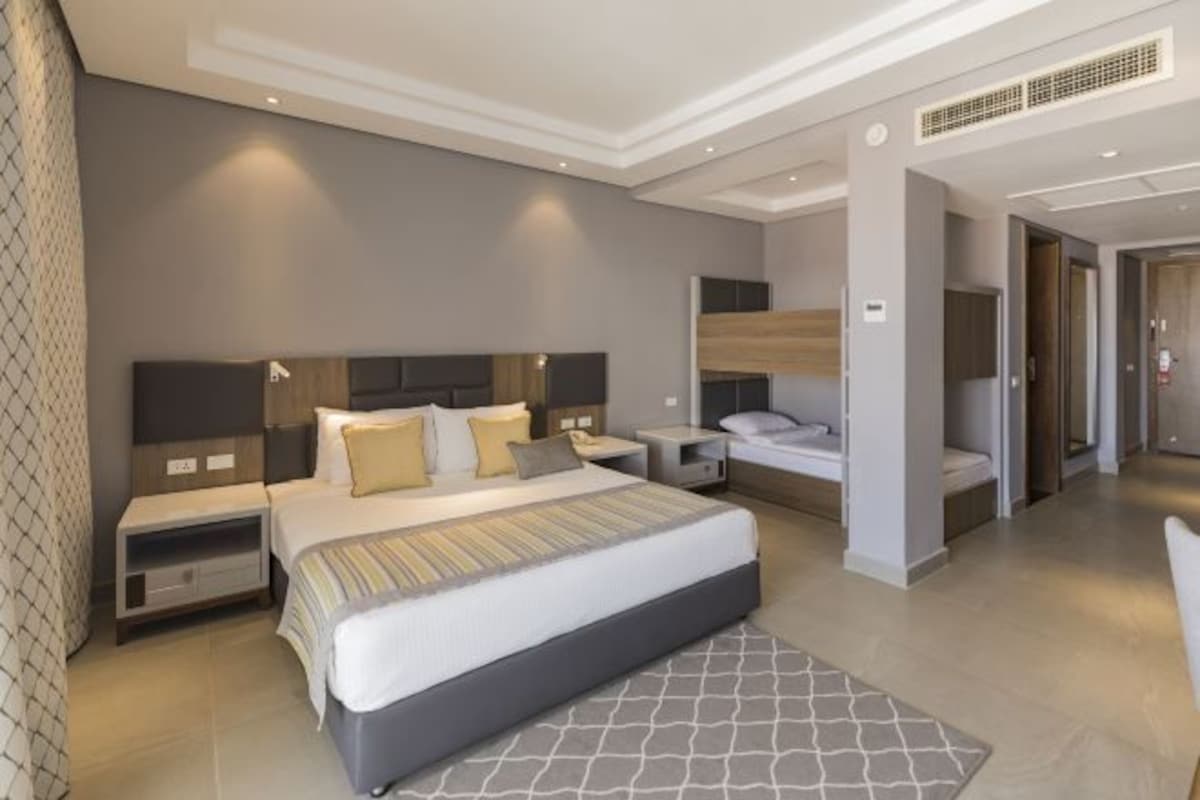 Habitación de hotel moderna con una cama grande, mesitas de noche y un vestidor.