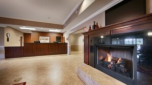 A lobby with a reception desk, a fireplace, and a clock on the wall. - Best Western Plus Louisa (Louisa)