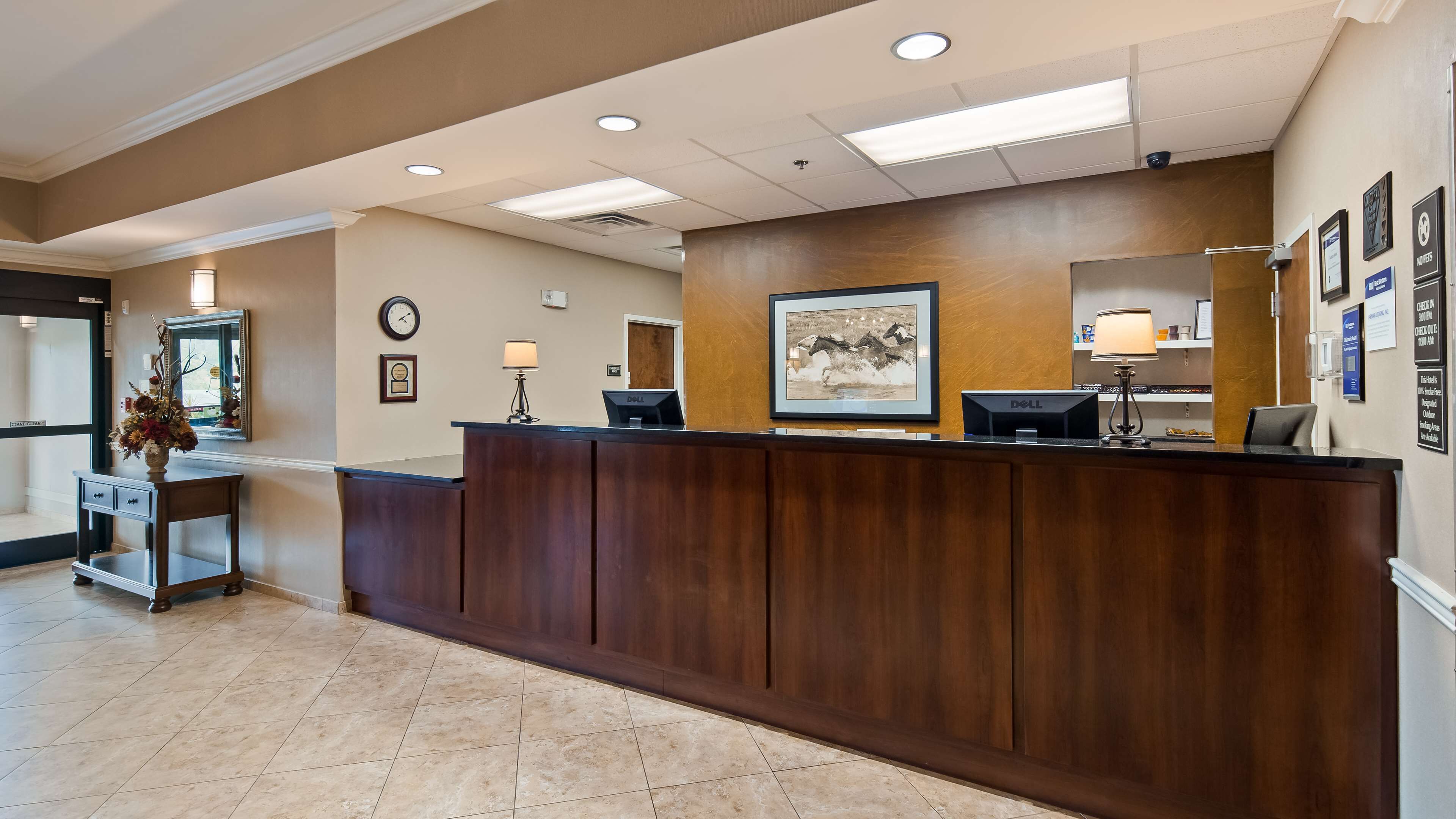 A reception area with a wooden reception desk, a clock, a framed picture, and a desk lamp.