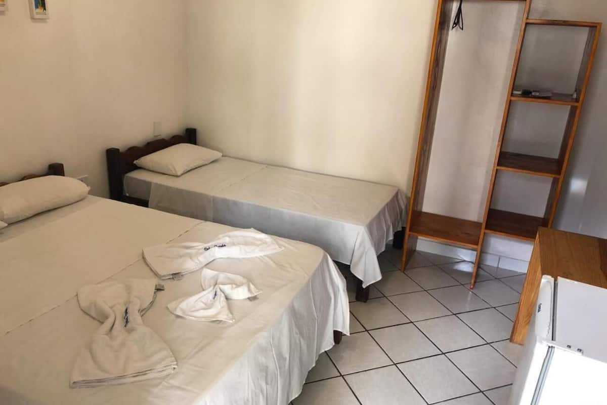Ein Zimmer mit zwei Betten, einer Holzleiter und einem gefliesten Boden.