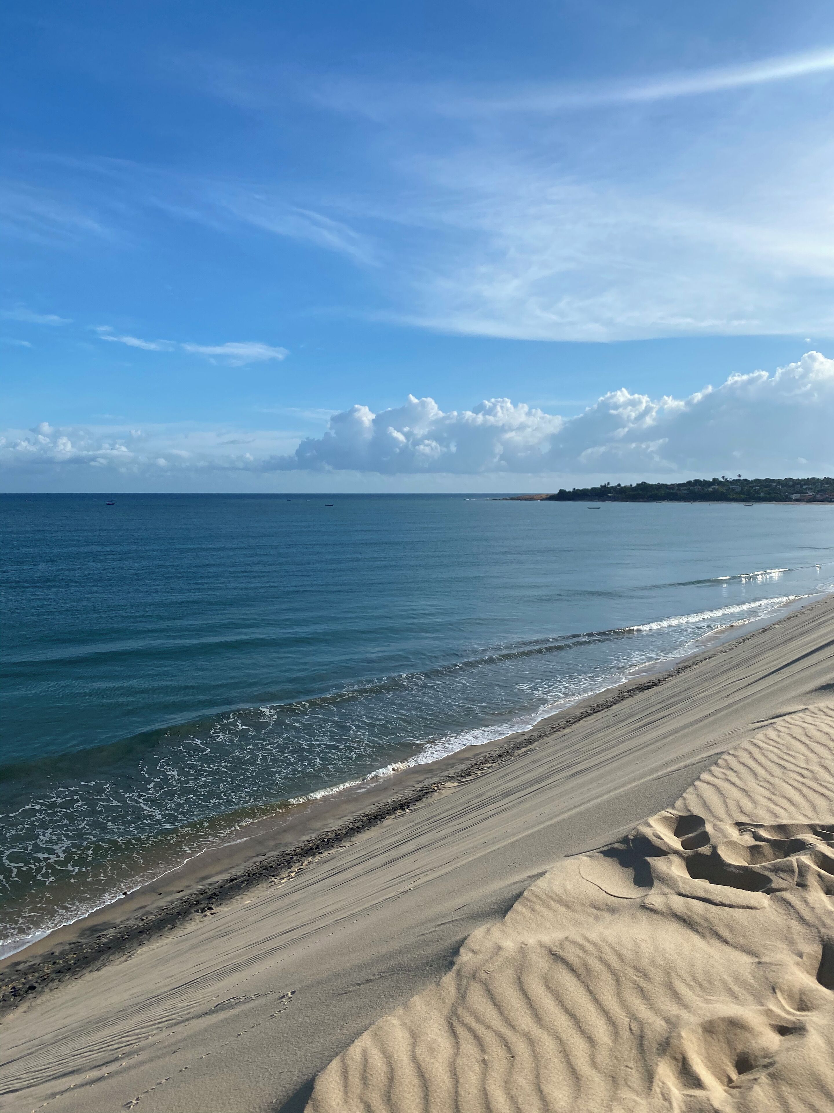 Una playa con cielo despejado, mar tranquilo y una costa distante.