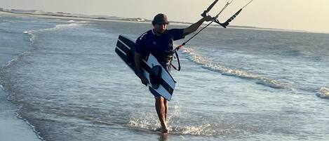 A person walking on a beach with a kiteboard.