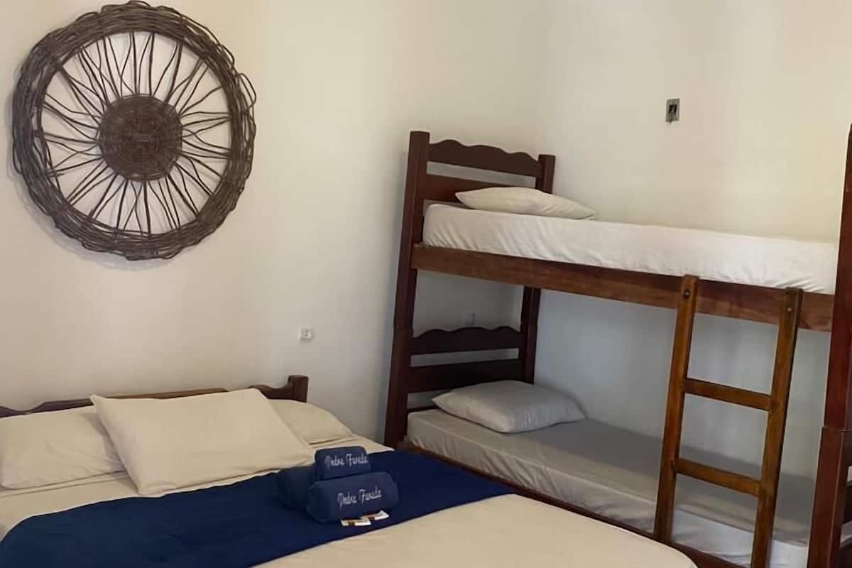 Ein Zimmer mit einem Etagenbett, einem Einzelbett mit blauer Decke und einer Wanddekoration.