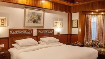 Een hotelkamer met een groot bed, houten wandpanelen, een plafondventilator en lijstwerken aan de muren.