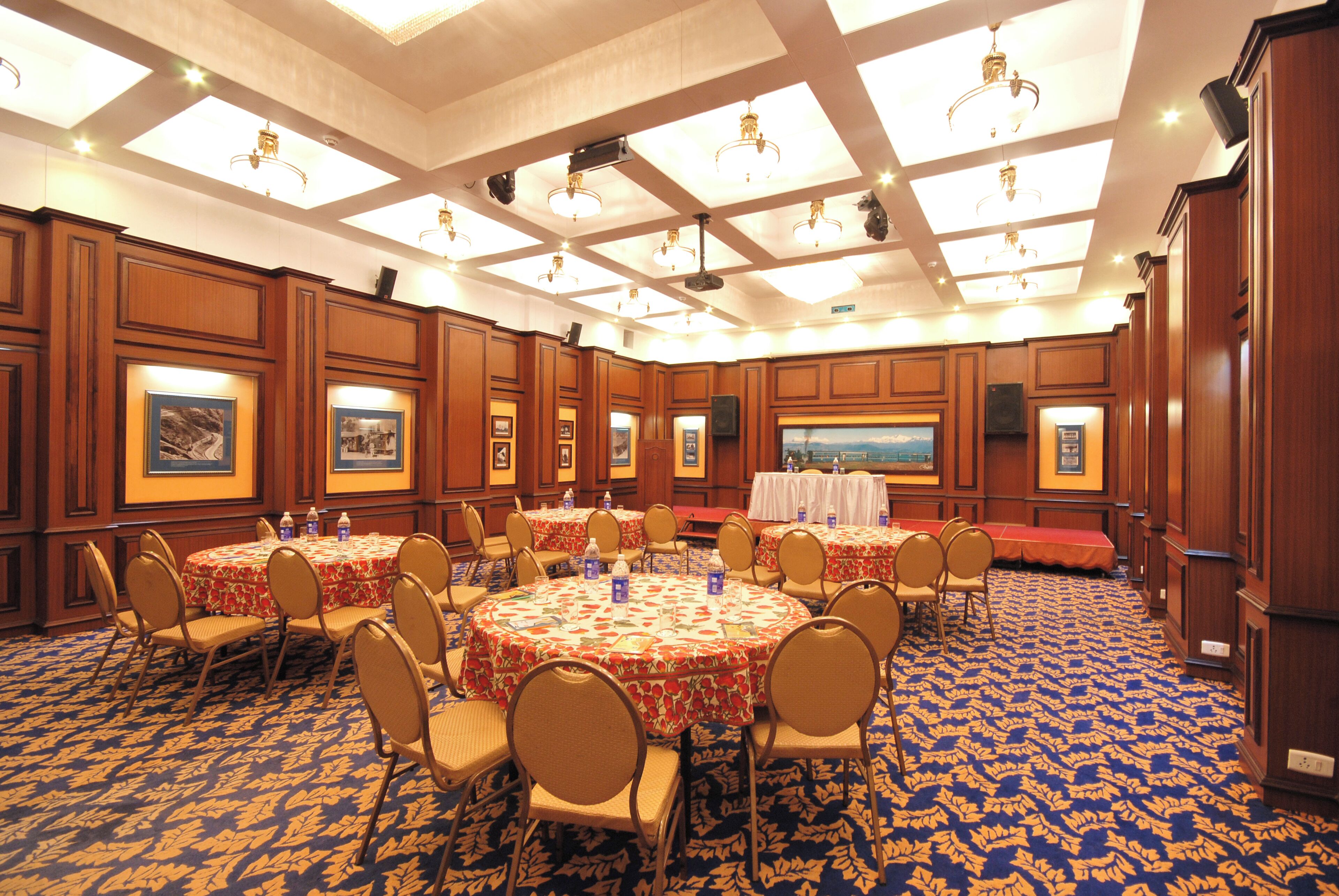 Een congreszaal met ronde tafels, stoelen en een podium.