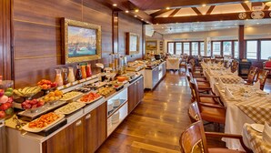 En buffet med forskellige retter og et langt spisebord med stole.
