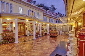 A spacious hotel lobby with a tiled floor, columns, and potted plants. - MAYFAIR Darjeeling (Darjeeling)