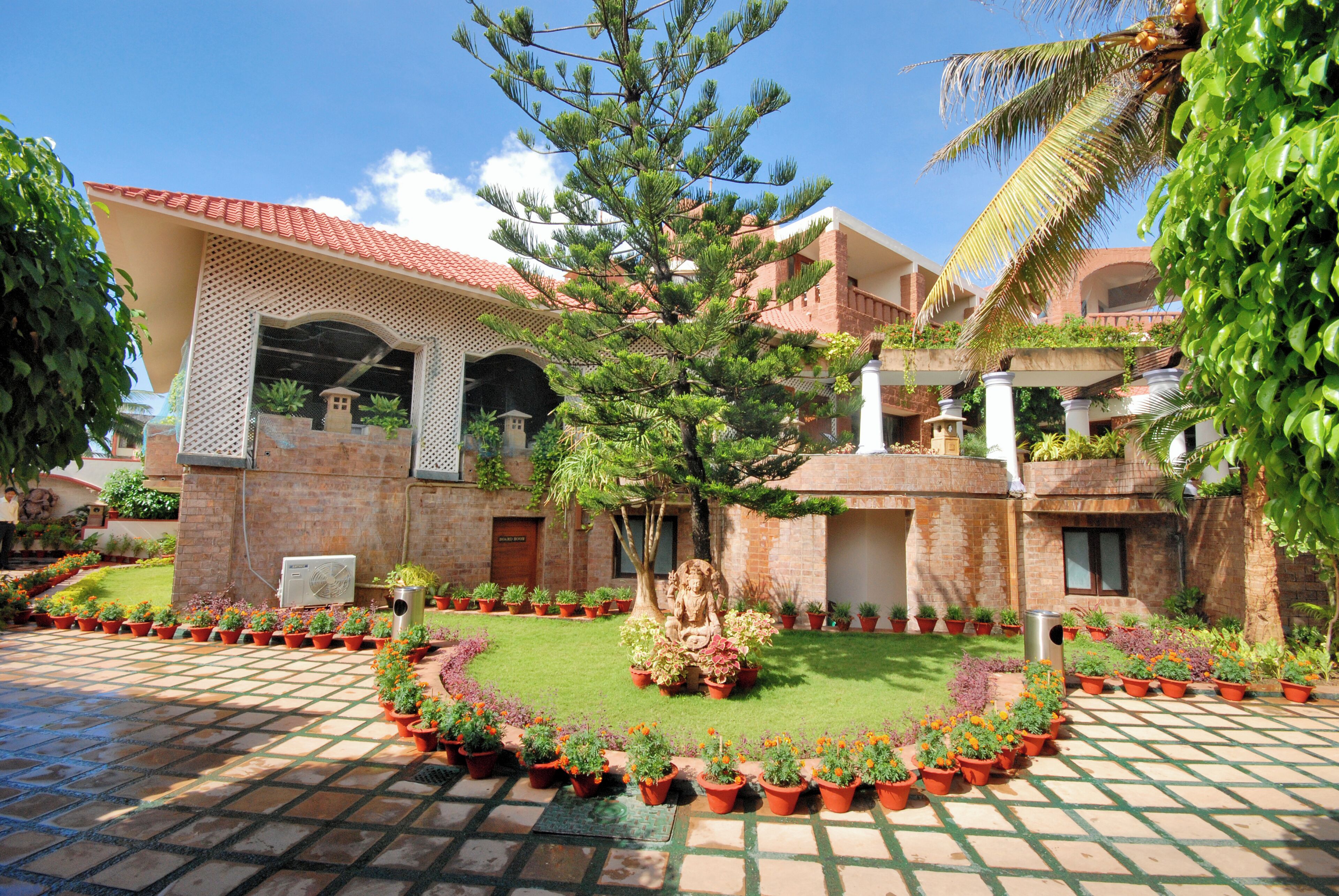 A courtyard with a central statue, surrounded by potted plants and a tiled floor.