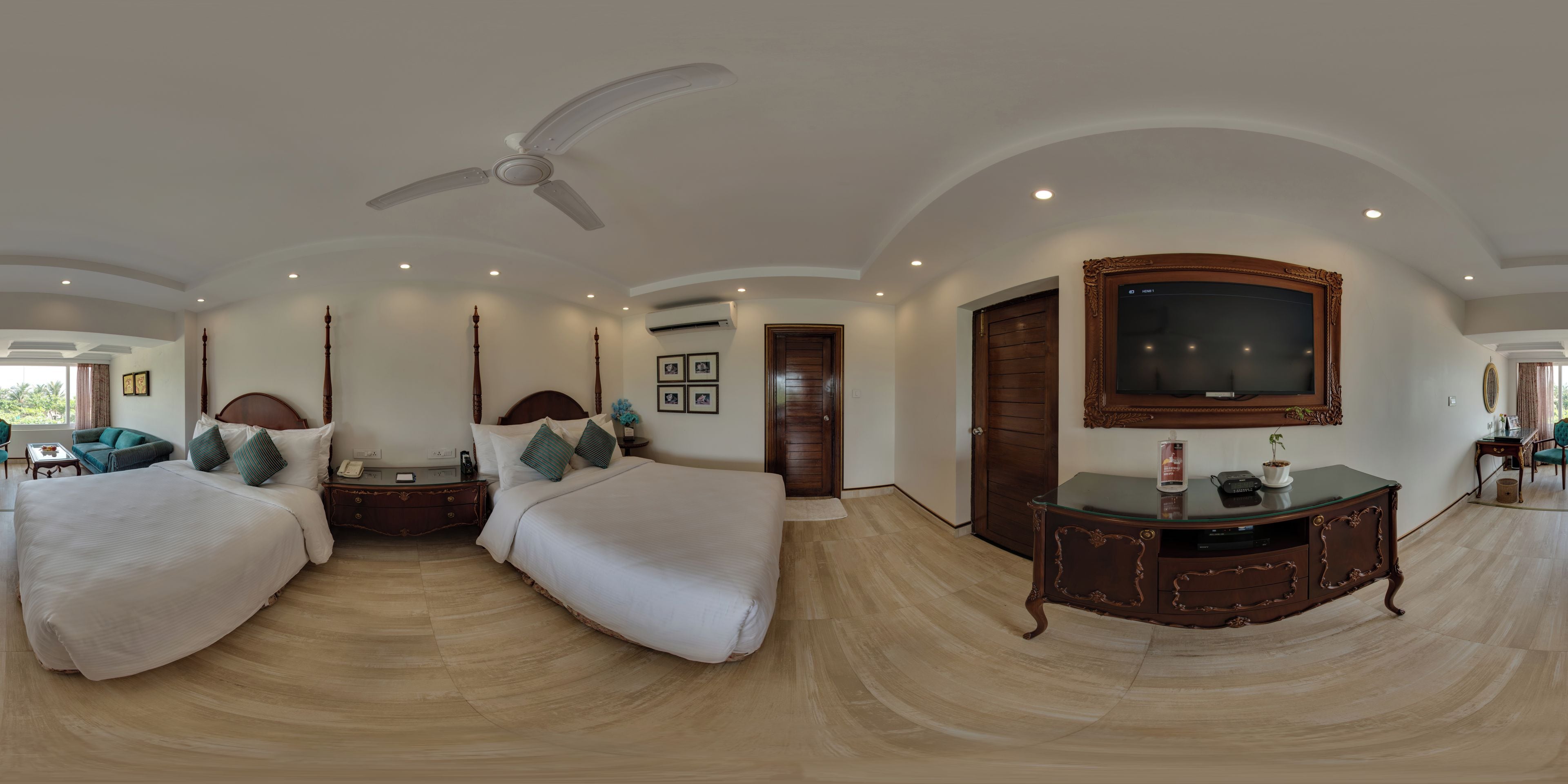A hotel room with a large bed, a bedside table, a ceiling fan, a TV, and a wooden cabinet.