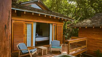 A wooden cabin with a balcony, a pool, and a bed visible inside.