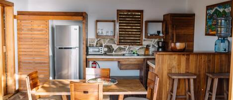 A rustic kitchen with wooden furniture, a refrigerator, a microwave, and a water dispenser.