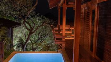 Una terraza de madera con un jacuzzi, sillas de madera y una pérgola.