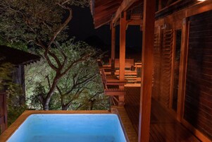 Una terraza de madera con un jacuzzi, sillas de madera y una pérgola.