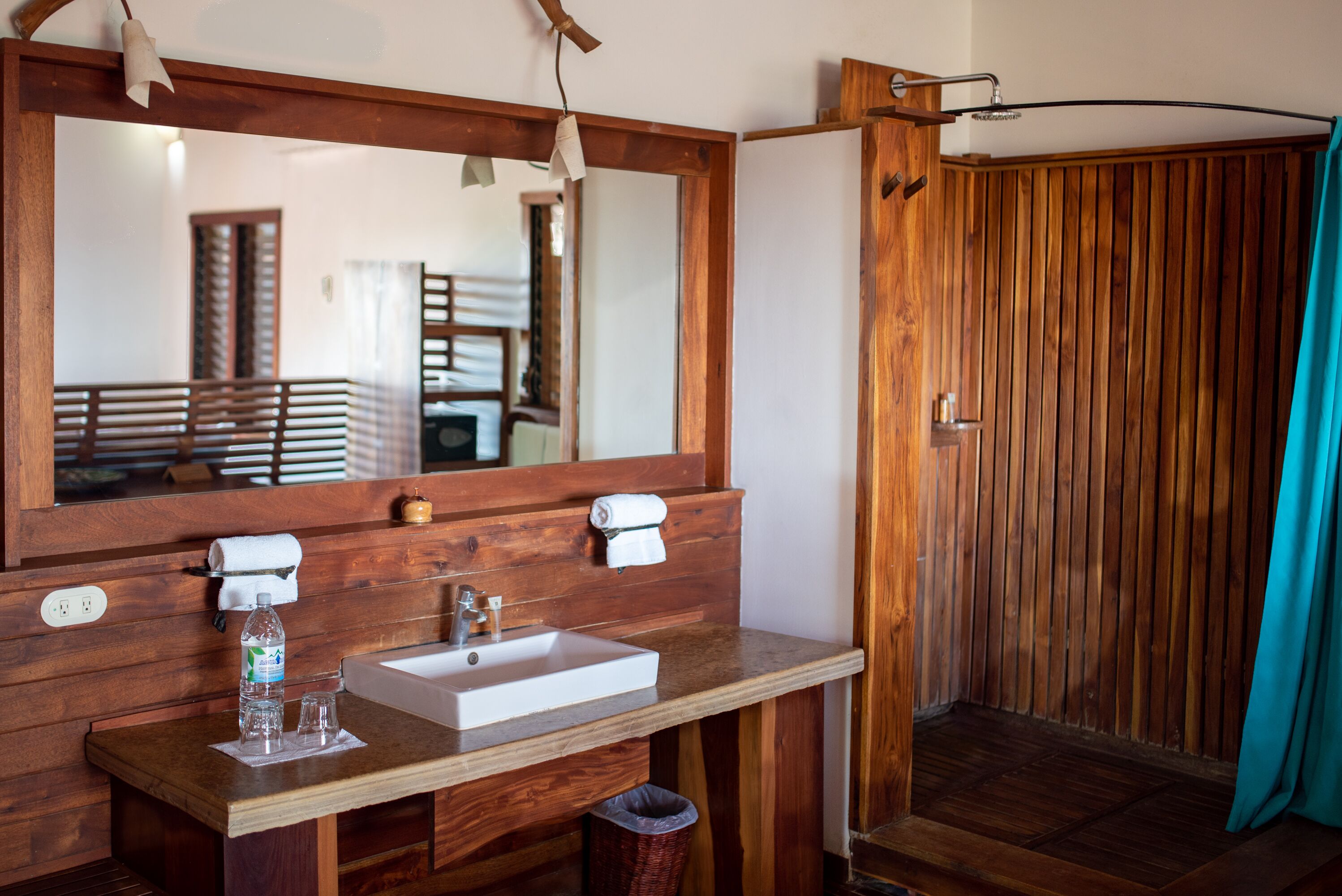 Un baño de madera con un espejo grande, un lavamanos y una zona de ducha.