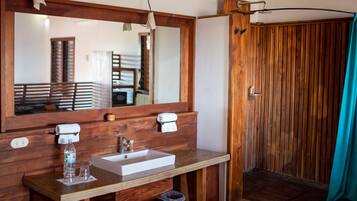 Un baño de madera con un espejo grande, un lavamanos y una zona de ducha.