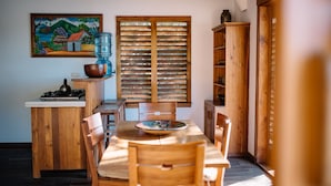 A wooden dining area with a table and chairs, a water dispenser, and a painting on the wall. - Aqua Oceanfront Hotel Resort (Tola)