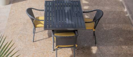 A patio with a table and chairs, a concrete floor, and a wooden bench.
