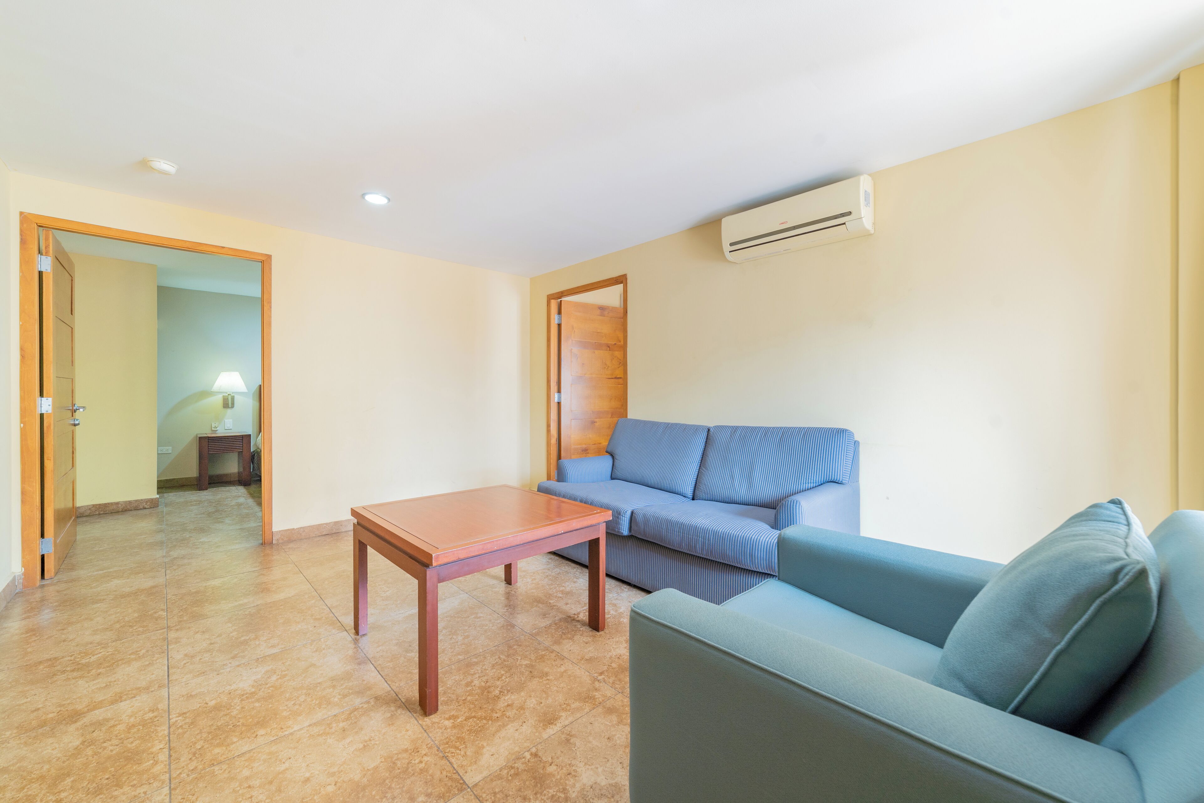 A living room with a blue sofa, a wooden coffee table, and a tiled floor.
