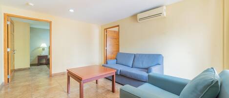 A living room with a blue sofa, a wooden coffee table, and a tiled floor.
