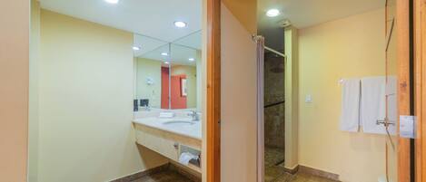 A bathroom with a large mirror, a sink, and a shower area.