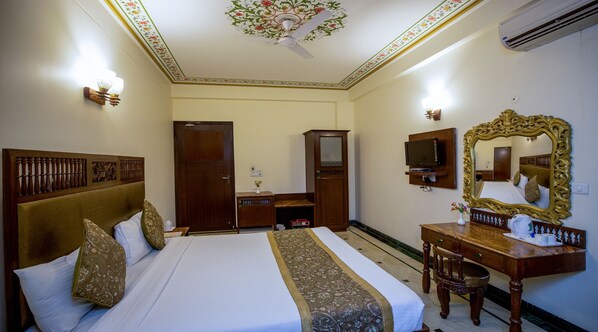 Una habitación de hotel con una cama grande, un aparador de madera, un televisor y un espejo.