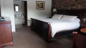 A hotel room with a wooden bed, a small round table, and a brick wall.