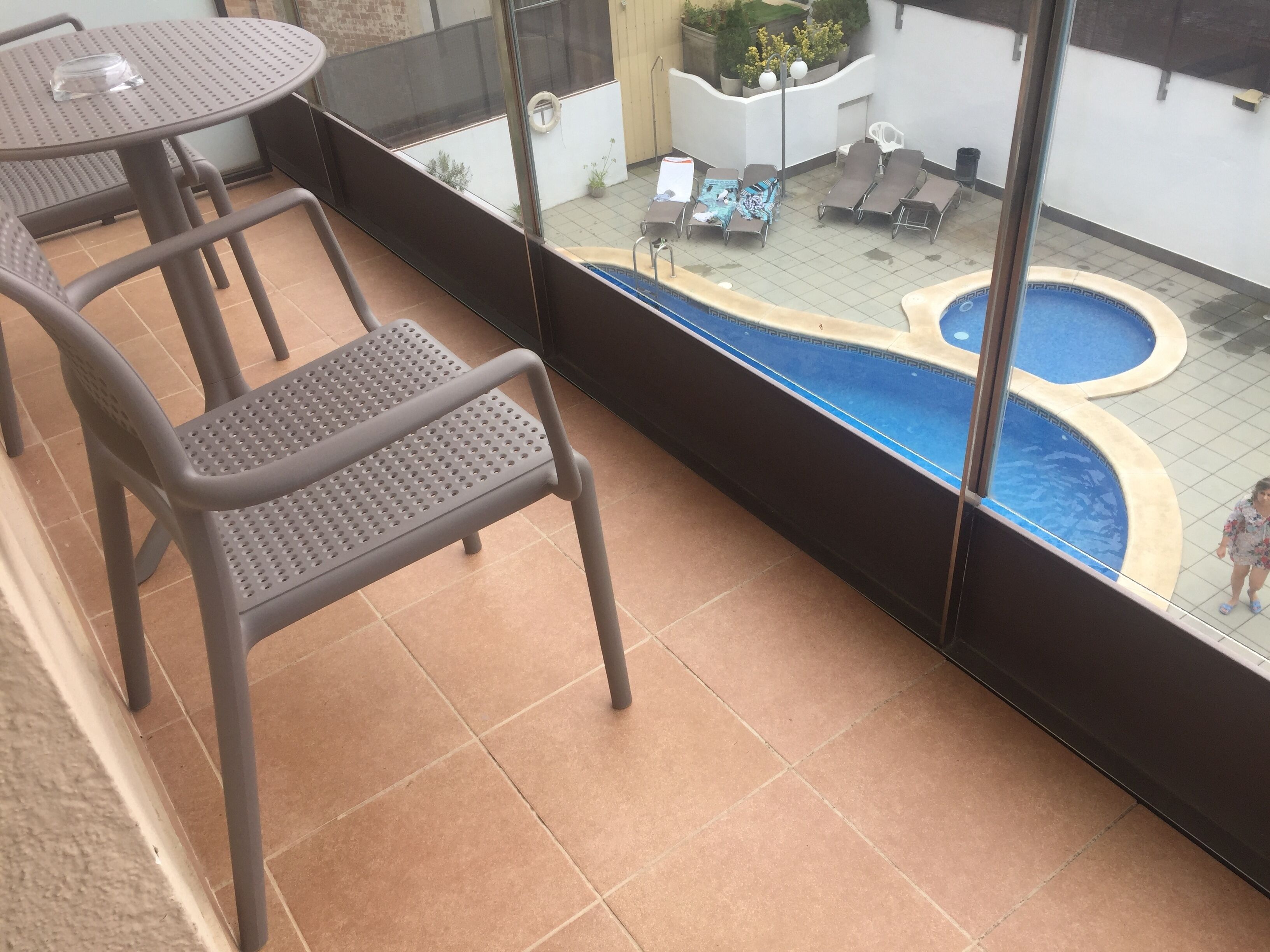 Un balcón con piscina, sillas y una mesa.