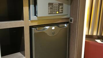 A compact refrigerator with a control panel, built into a wooden cabinet with a television above it.