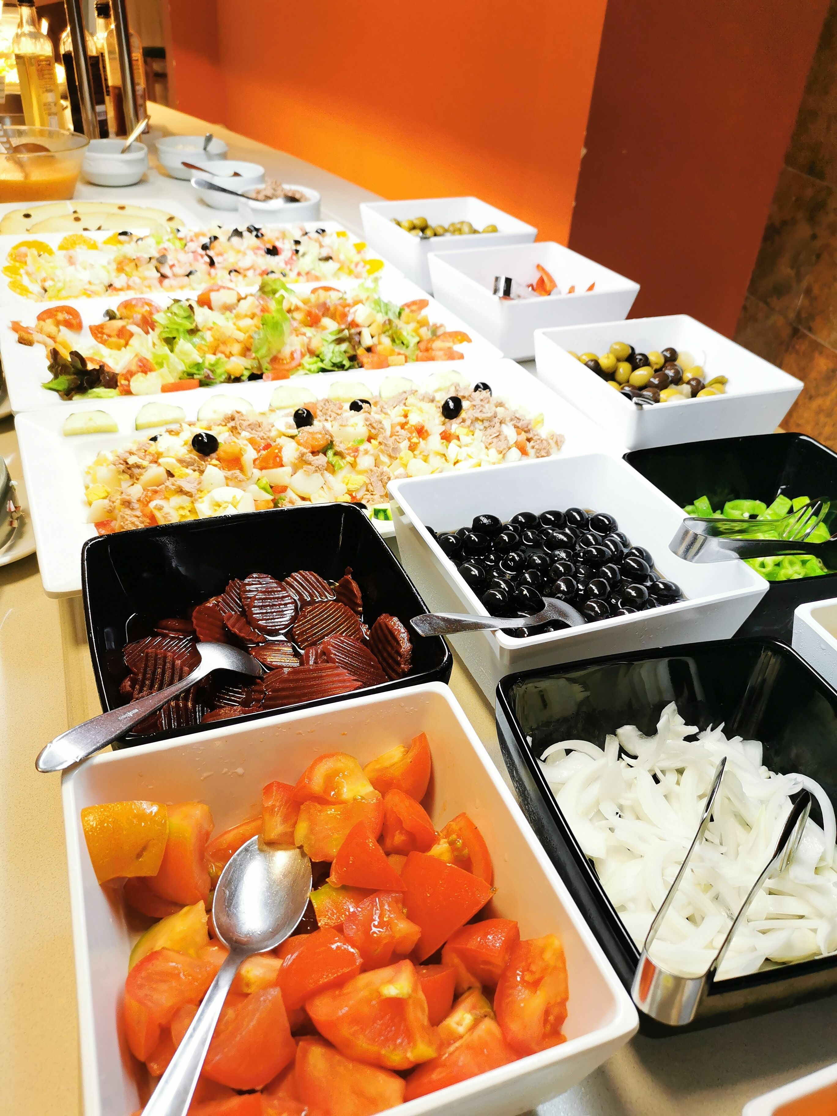 A buffet with various dishes including salads, fruits, and vegetables.
