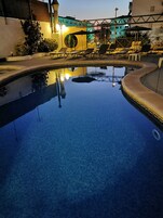 Una piscina al aire libre, sillones reclinables de piscina