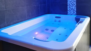 A modern bathroom with a freestanding bathtub, blue LED lighting, and a mosaic tile accent wall. - Petit Palau - Adults Only (Blanes)