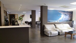 A modern hotel lobby with a reception desk, seating area, and a large cityscape mural on the wall. - Petit Palau - Adults Only (Blanes)