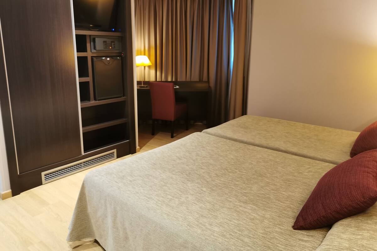 A hotel room with a bed, a desk, and a wardrobe.