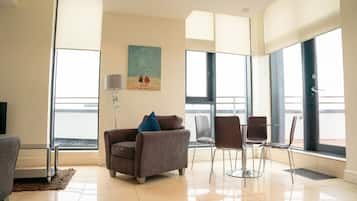 Una sala de estar moderna con un sofá, sillas, una lámpara y un cuadro en la pared.