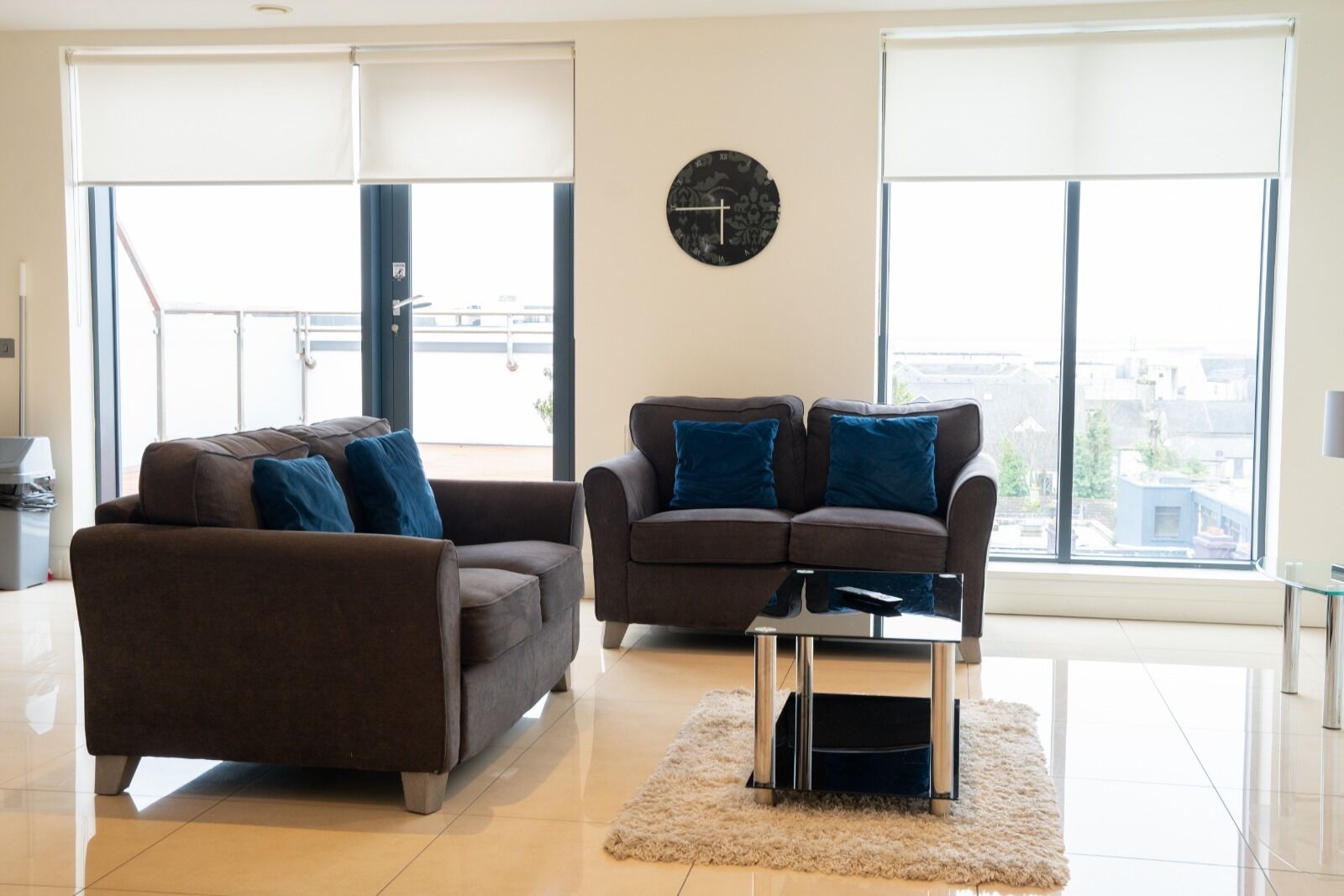 A modern living room with two sofas, a coffee table, and a large window with a view of buildings.