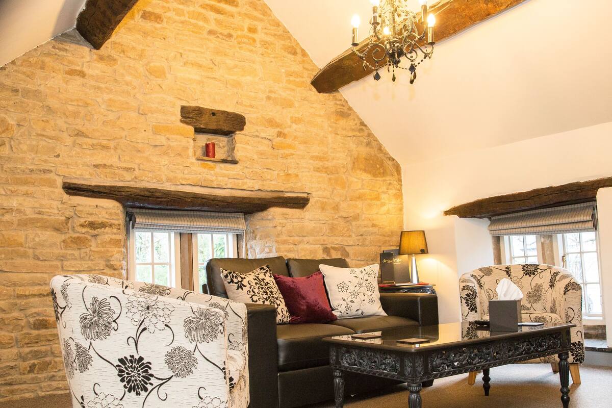 A cozy room with a stone wall, a chandelier, a sofa, and a coffee table.