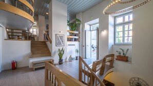 A spacious interior with a wooden staircase, a dining area, and a large window with natural light. - Grand Sarai Nafplio (Nafplio)