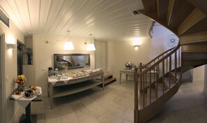 Habitación de hotel con comedor, baño con espejo y escalera de madera.