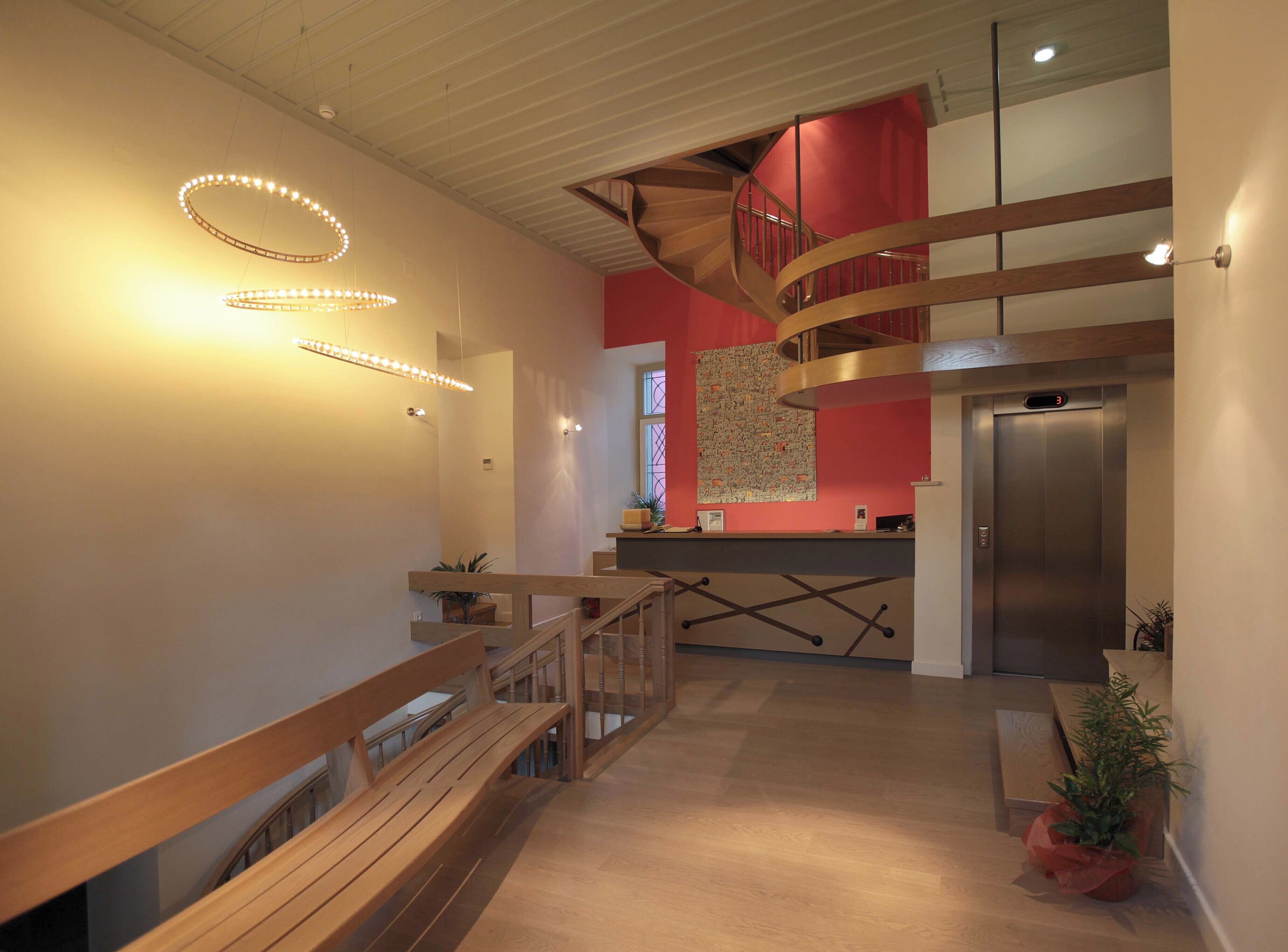Ein modernes Interieur mit einer Holztreppe, einem Empfangsbereich und einem Aufzug.