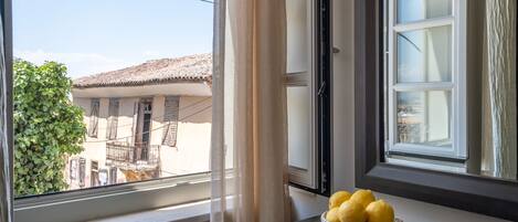 A window with a view of a building and a basket of lemons on a table.