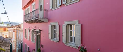 Ein rosafarbenes Gebäude mit vielen Fenstern und einem Balkon.