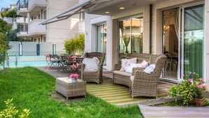 Un patio moderno al aire libre con mobiliario de mimbre, una piscina y una puerta de cristal que da a un comedor.