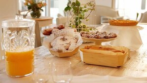 Una mesa con pasteles, un vaso de zumo de naranja y una jaula con plantas.